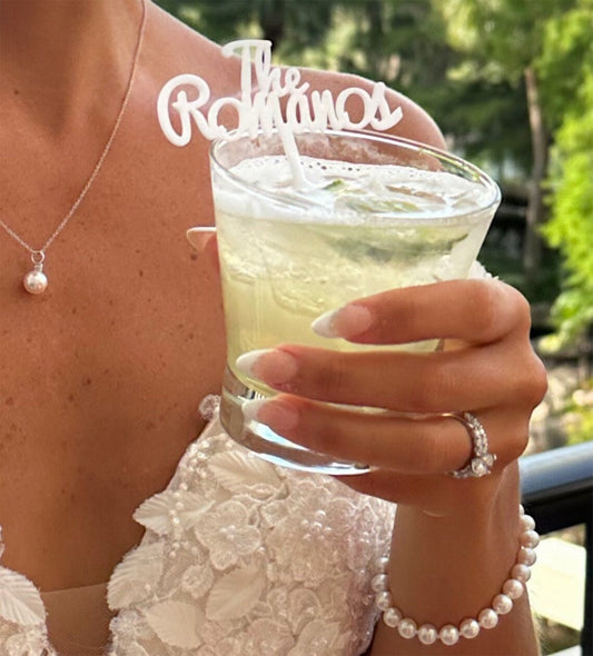 White custom wedding drink stirrer with elegant design, placed in a cocktail glass.