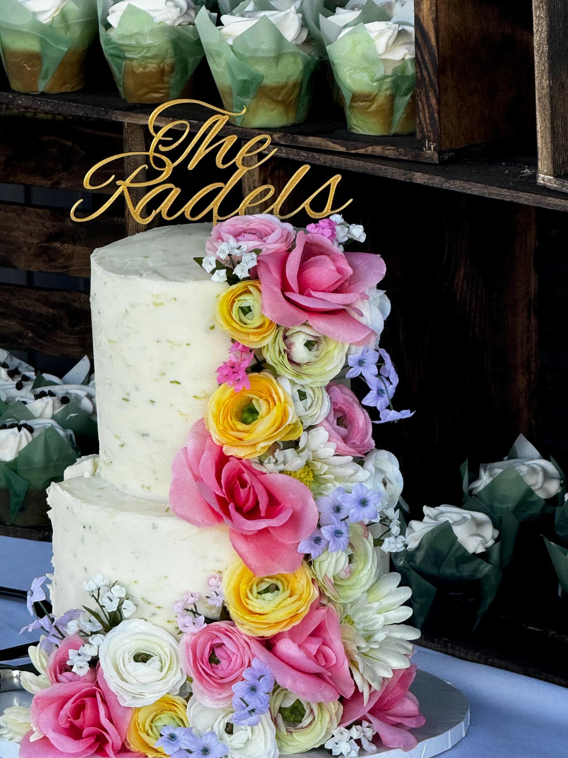 Close-up of custom wedding cake topper with initials and intricate details placed on top of a wedding cake.